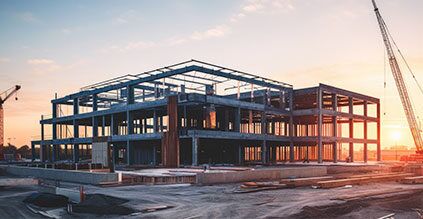 A large commercial building under construction at sunset, featuring a steel frame structure with multiple floors.